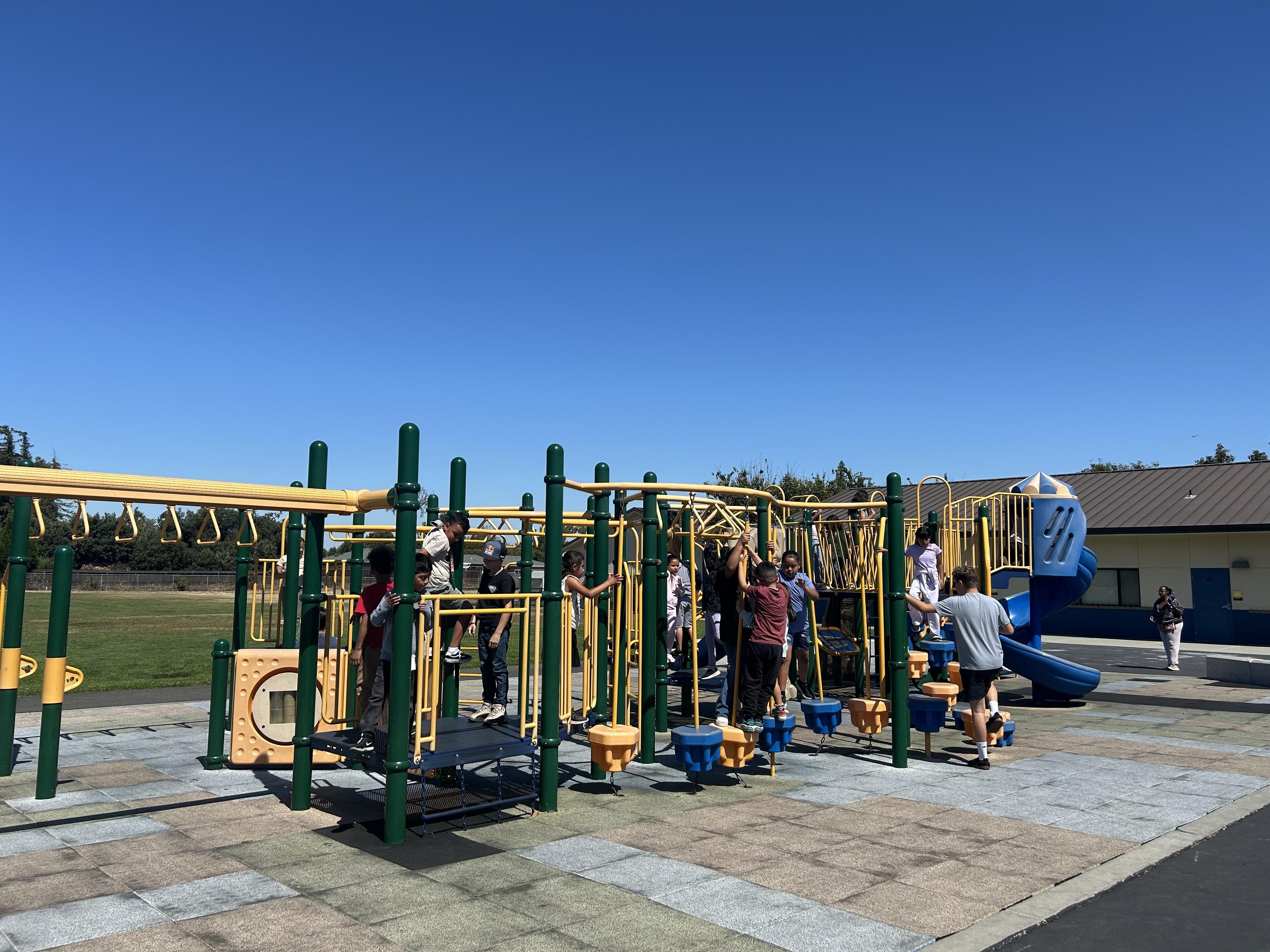 Children playing on a play structure at a school playground.