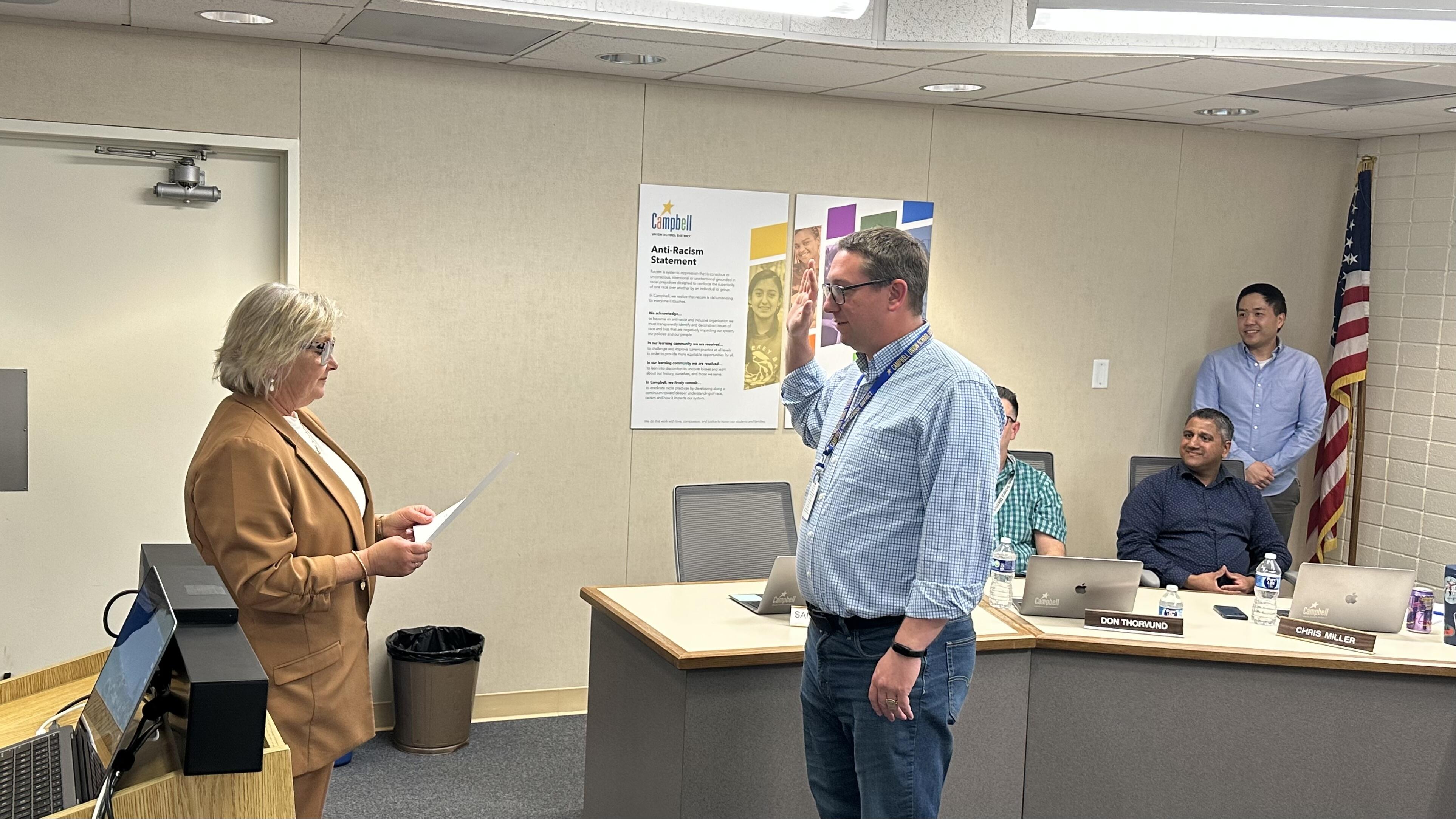 Area 5 trustee Sam Krow-Lucal is taking the oath of office. The oath is presented by Superintendent Viramontez and fellow board members are looking on.