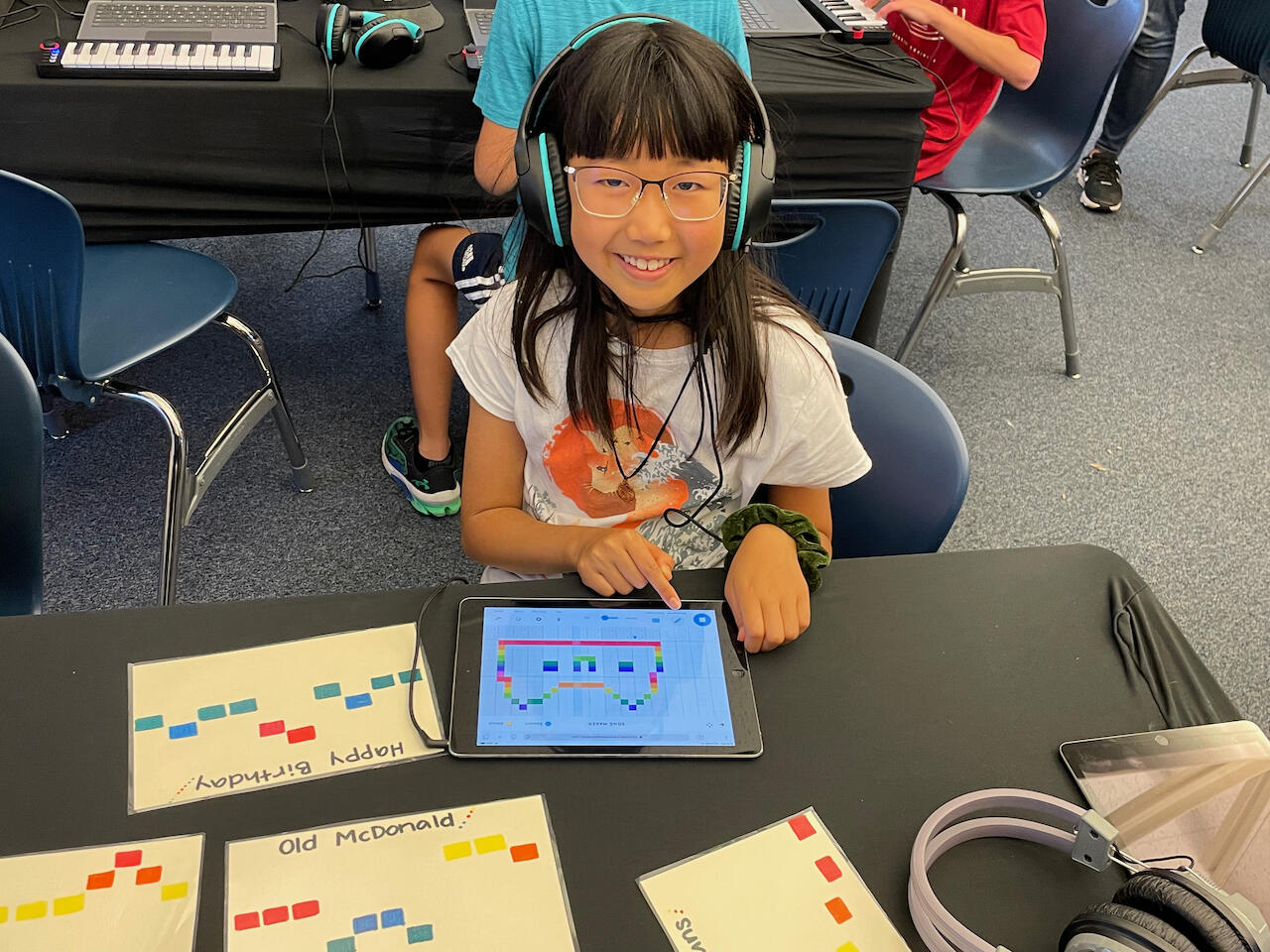 young girl wearing headphones and using a computer device to make music