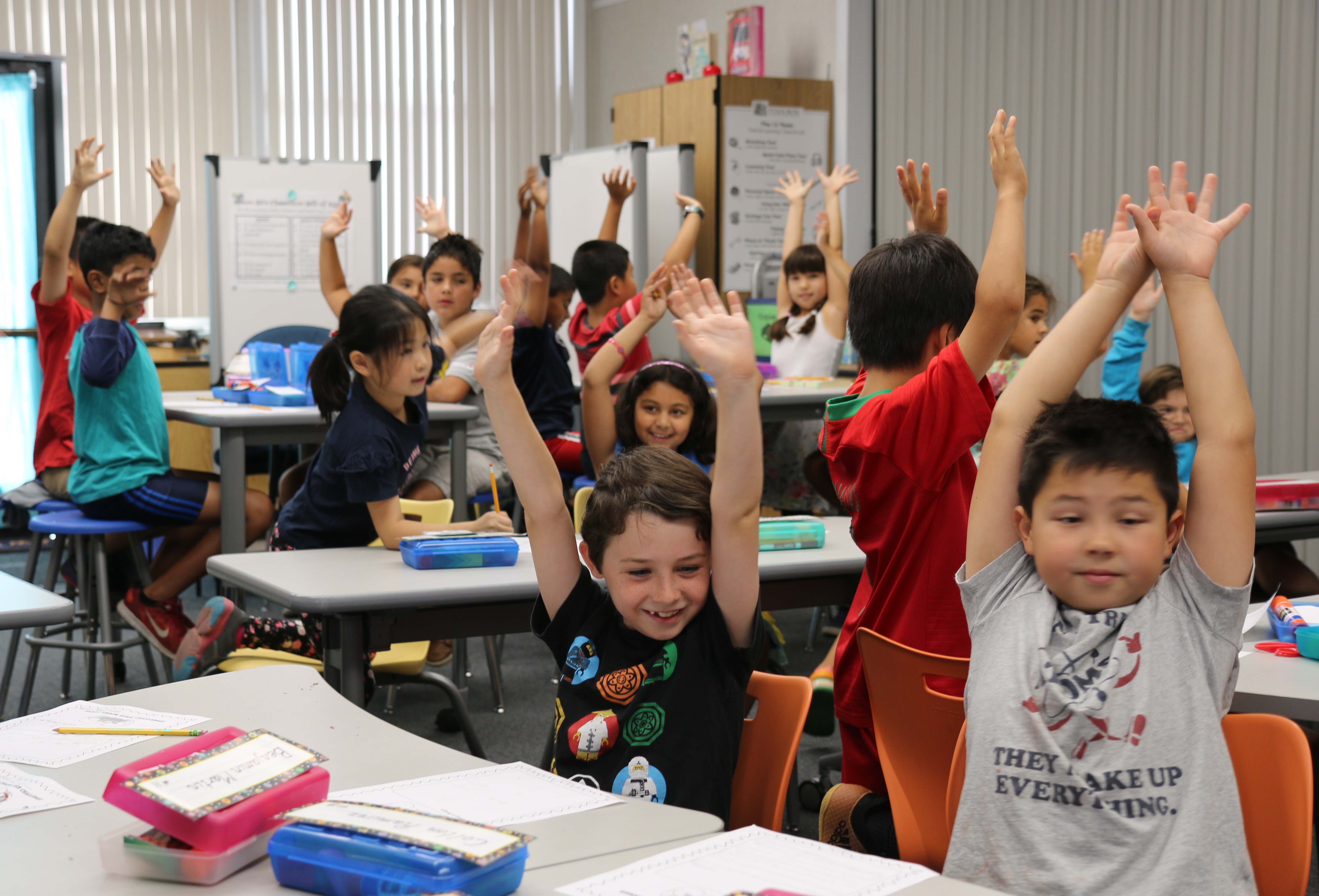 smiling students with hands up