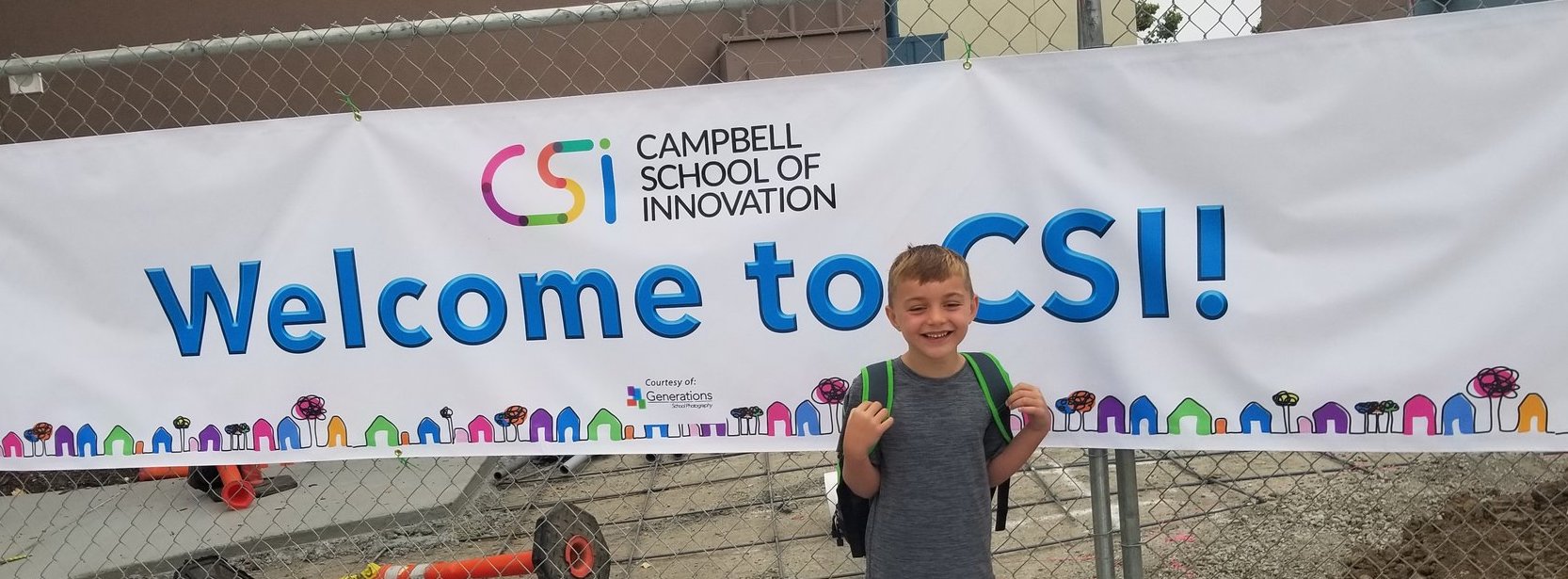 young boy with backpack in front of welcome banner