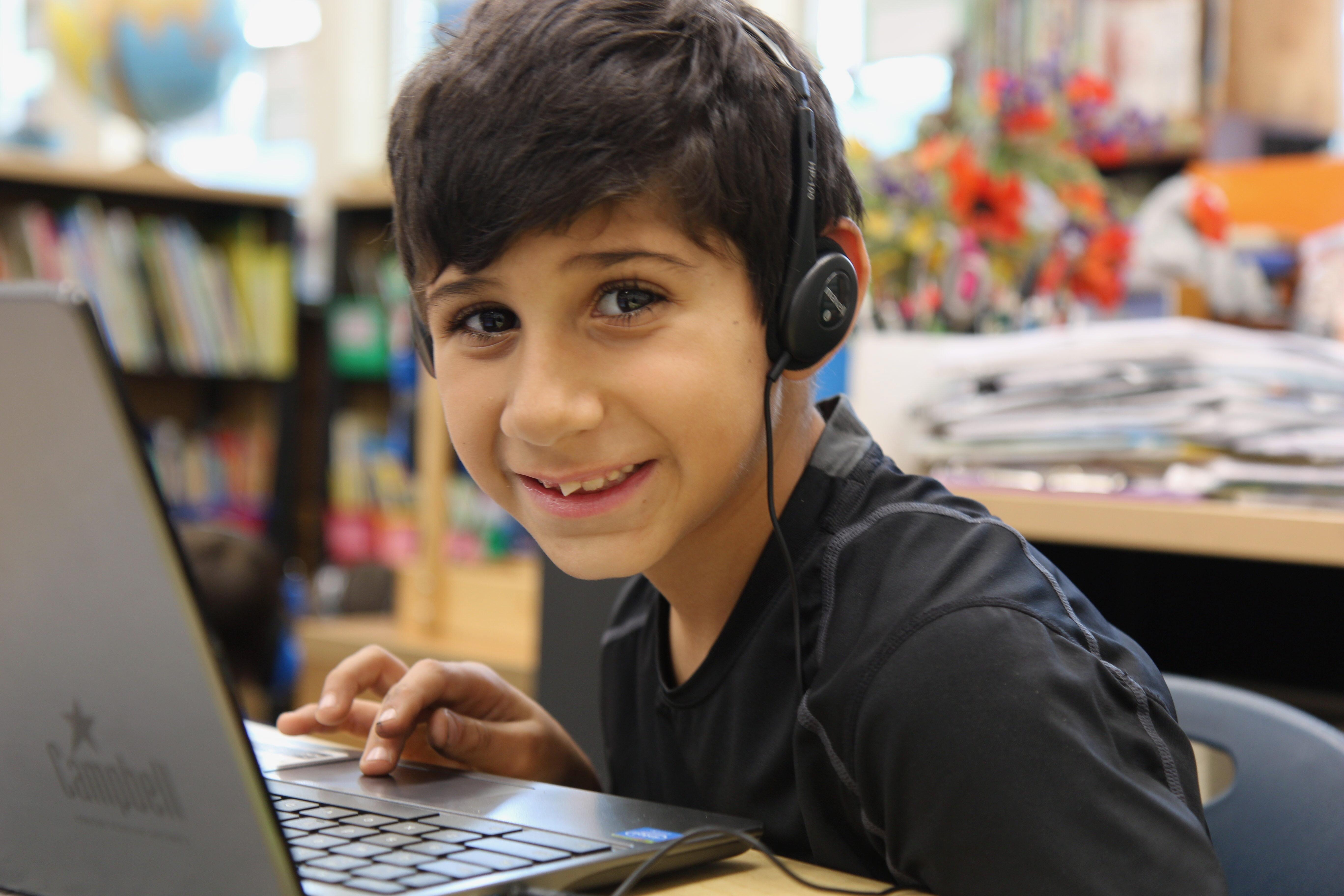 smiling boy with laptop and wearing headphones