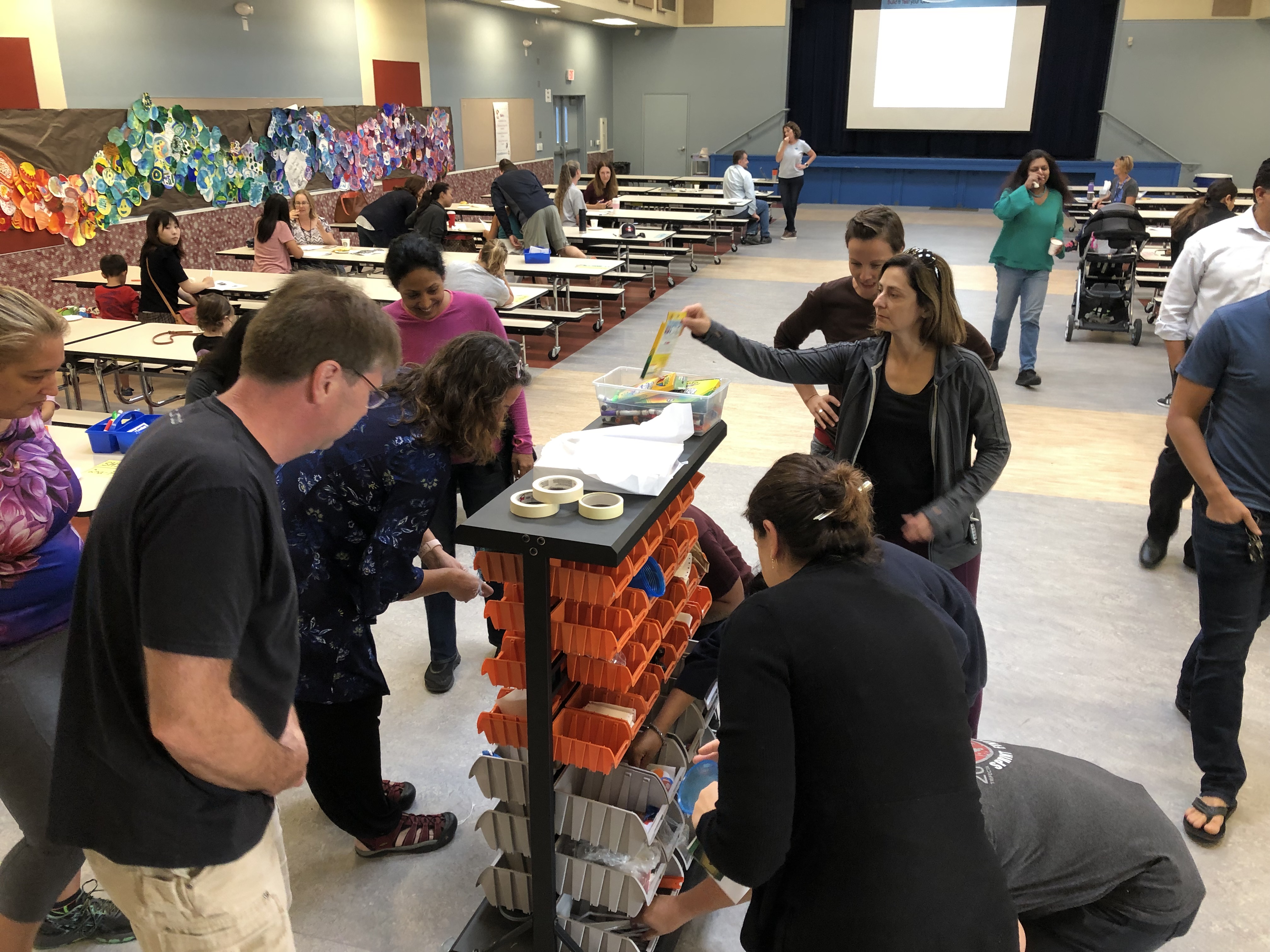 Adults getting items from supply cart.