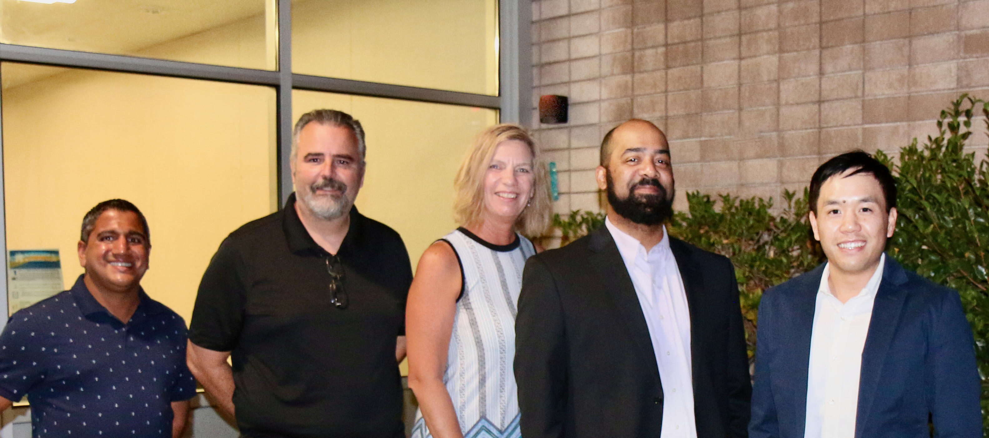 4 men and 1 woman standing together and smiling