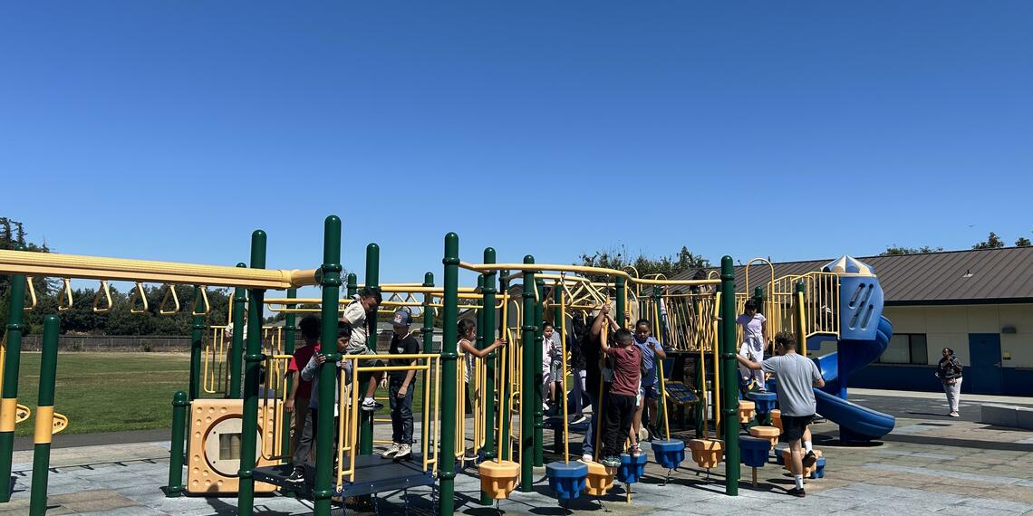 Children playing on a play structure at a school playground.