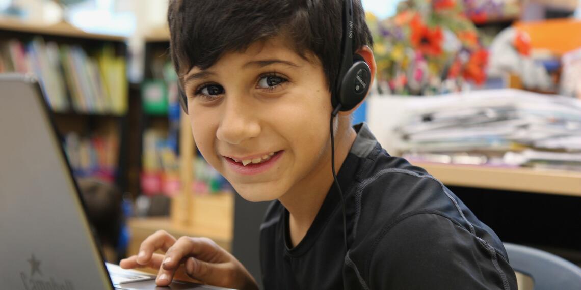 smiling boy with laptop and wearing headphones