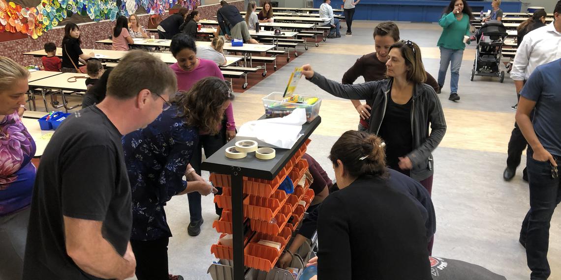 Adults getting items from supply cart.