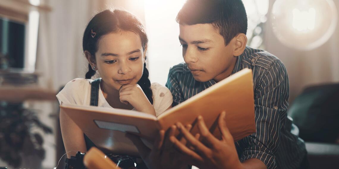 brother and sister reading together at home